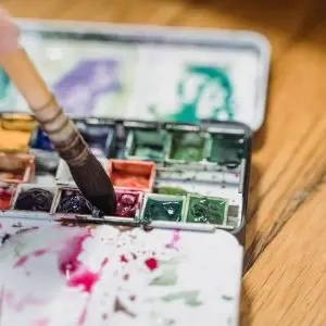 Close-up of a watercolor palette with a paintbrush, showcasing vibrant colors and artistic creativity.
